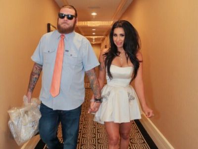 Korina Harrison and Corey Harrison are holding hands as they are walking in a hallway.